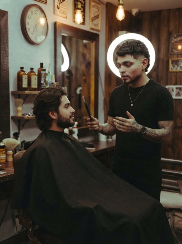 Barbero conversa con el cliente sentado en el sillón antes de empezar el corte
